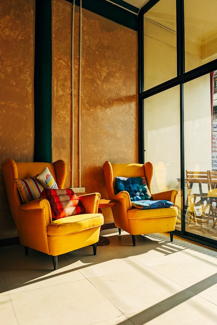 Bright yellow armchairs with colorful cushions in a sunny, modern living room.